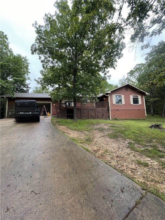 view of home's exterior featuring asphalt driveway, a wooden deck, and a yard