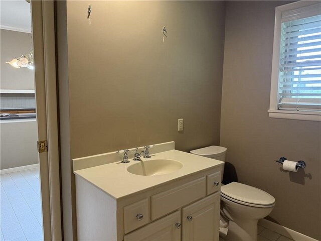 bathroom featuring toilet, vanity, tile patterned floors, baseboards, and ornamental molding