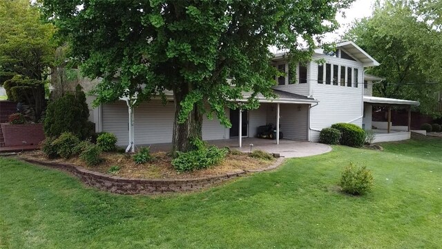 back of property featuring a yard, a patio area, and a sunroom