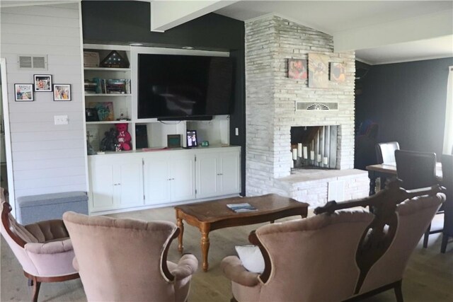 living room featuring a fireplace, crown molding, and wood finished floors
