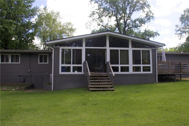 back of house featuring a wooden deck, a lawn, and a sunroom