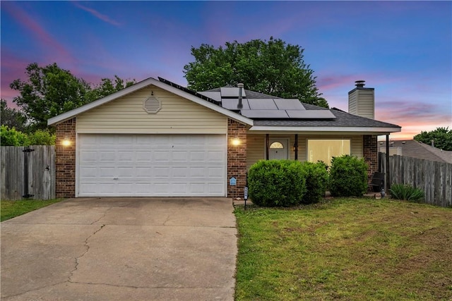 view of front of property with brick siding, solar panels, concrete driveway, a chimney, and a garage