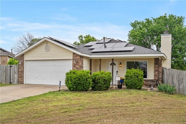 single story home featuring brick siding, a garage, driveway, and roof mounted solar panels