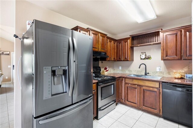 kitchen with appliances with stainless steel finishes, a sink, light tile patterned floors, under cabinet range hood, and stone countertops