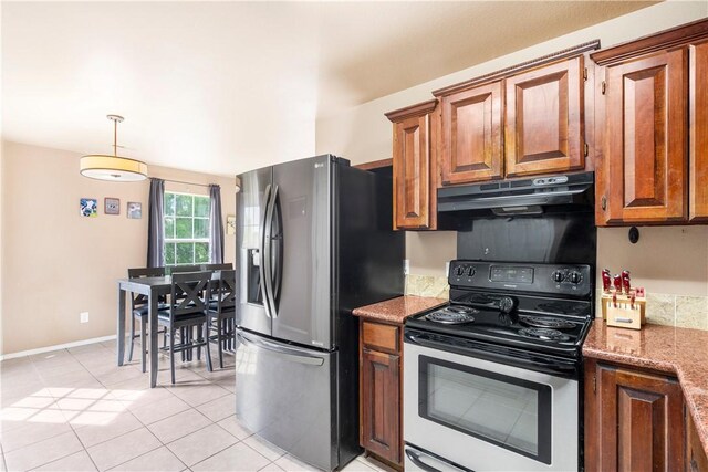 kitchen featuring appliances with stainless steel finishes, under cabinet range hood, brown cabinetry, light tile patterned floors, and stone counters