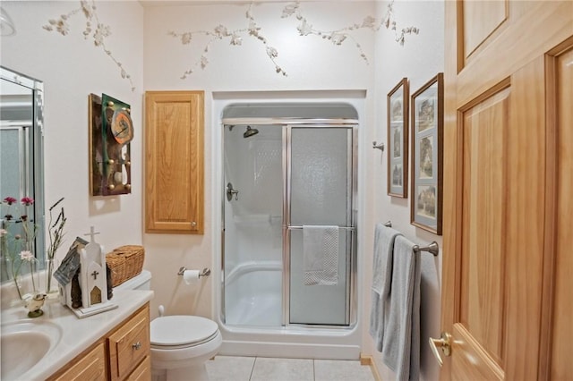 bathroom featuring tile patterned flooring, a stall shower, vanity, and toilet