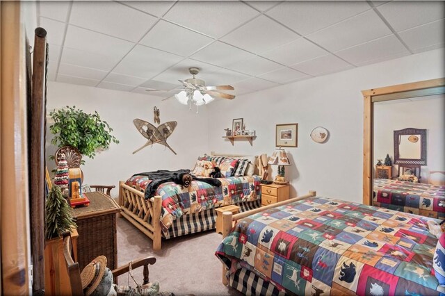 carpeted bedroom with a paneled ceiling and ceiling fan