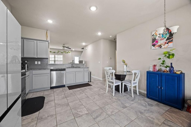 kitchen featuring stainless steel dishwasher, a sink, a ceiling fan, a peninsula, and light stone countertops