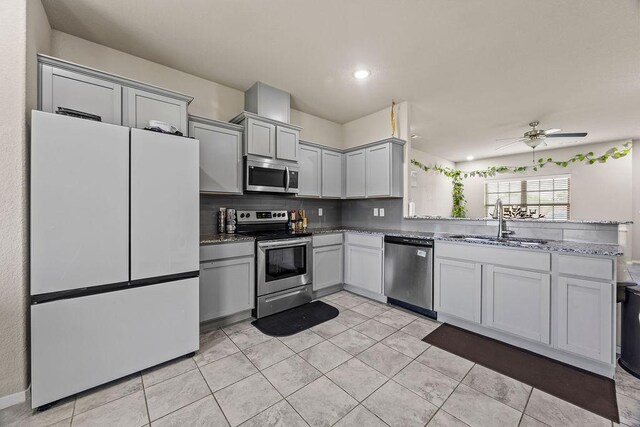 kitchen with stainless steel appliances, a sink, ceiling fan, light tile patterned floors, and backsplash