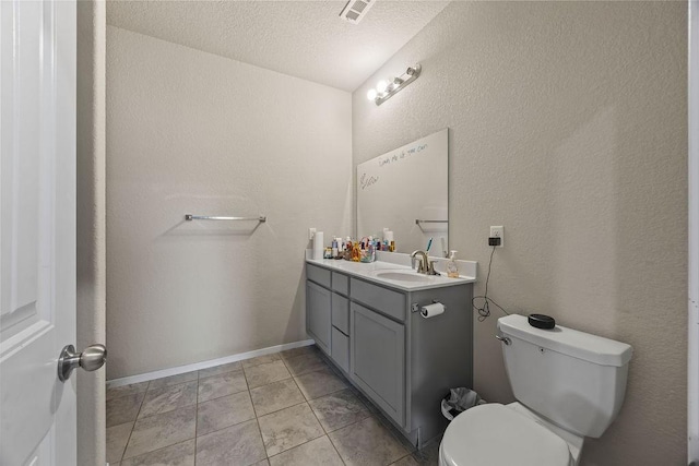 bathroom with toilet, vanity, a textured wall, and a textured ceiling