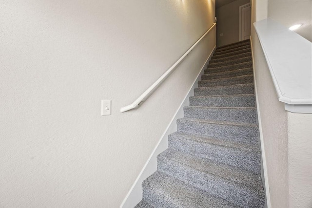 stairway with carpet flooring and a textured wall
