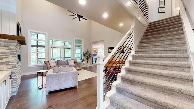 stairway with a high ceiling, wood finished floors, baseboards, and recessed lighting