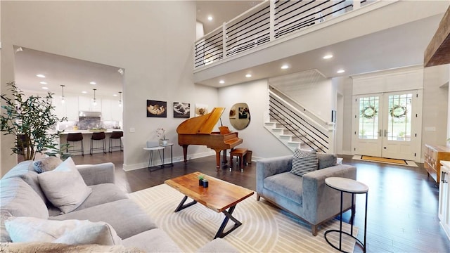 living area featuring wood finished floors, recessed lighting, stairs, baseboards, and a high ceiling