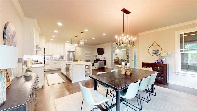 dining room featuring light wood-type flooring, ornamental molding, recessed lighting, and a chandelier