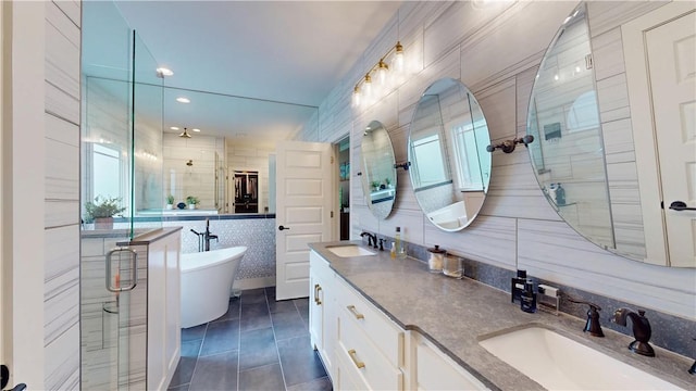full bath with a stall shower, a freestanding tub, double vanity, tile patterned flooring, and tile walls