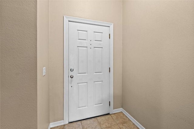 doorway to outside with baseboards and light tile patterned floors
