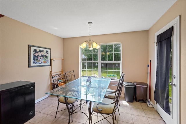dining space with a chandelier, light tile patterned floors, and baseboards