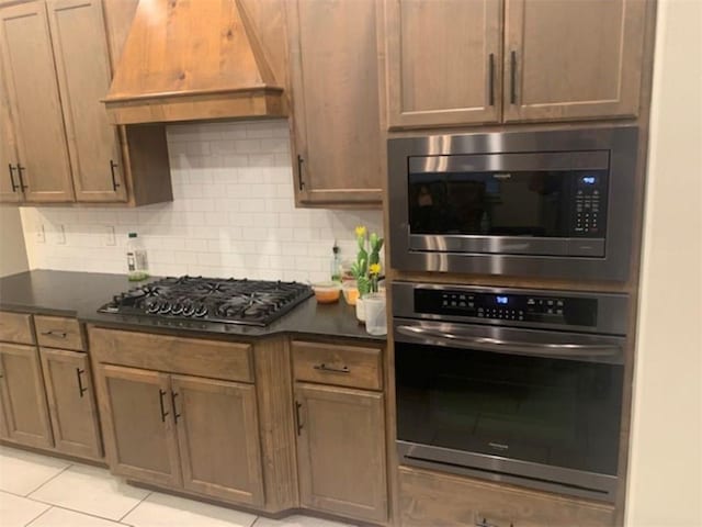 214 Hunt St, Pea Ridge, AR 72751 - kitchen featuring appliances with stainless steel finishes, backsplash, premium range hood, dark countertops, and light tile patterned floors