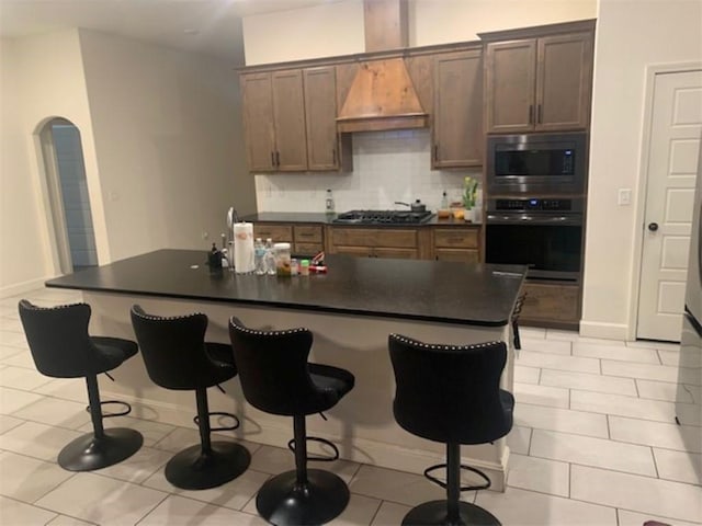 214 Hunt St, Pea Ridge, AR 72751 - kitchen featuring appliances with stainless steel finishes, a kitchen bar, backsplash, dark countertops, and custom exhaust hood