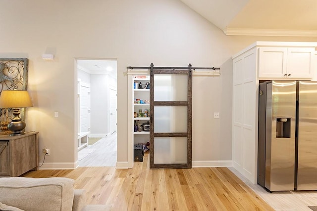 29 Salen Ln, Bella Vista, AR 72715 - interior space with stainless steel fridge, light wood finished floors, vaulted ceiling, a barn door, and white cabinetry