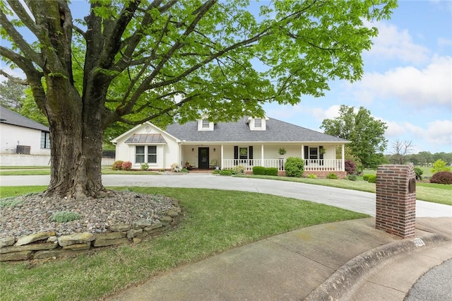 view of front of house featuring covered porch, curved driveway, a front yard, roof with shingles, and stucco siding