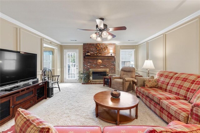 living room featuring a decorative wall, crown molding, a fireplace, healthy amount of natural light, and light carpet
