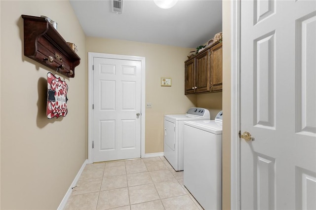 laundry area with separate washer and dryer, cabinet space, light tile patterned floors, and baseboards