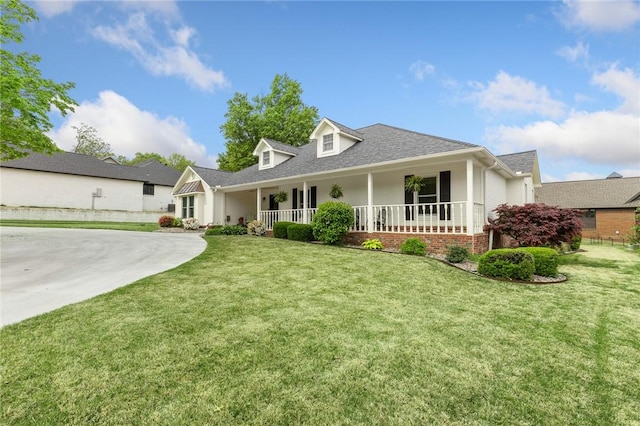 view of front of home with covered porch, a front yard, and roof with shingles