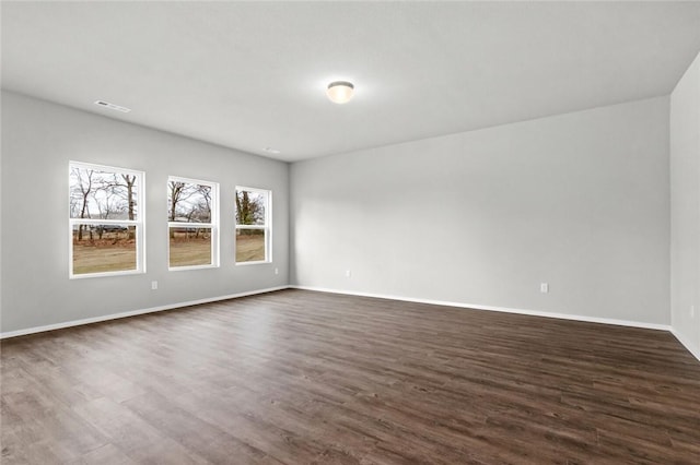 spare room featuring dark wood finished floors and baseboards