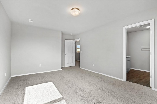 unfurnished bedroom with carpet floors, a spacious closet, and baseboards