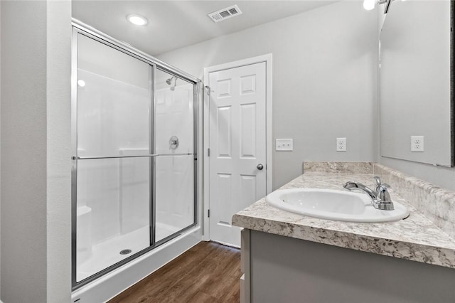 full bath featuring a shower stall, wood finished floors, and vanity