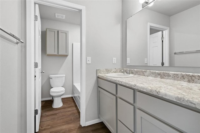 full bath with toilet, vanity, wood finished floors, baseboards, and a bathtub