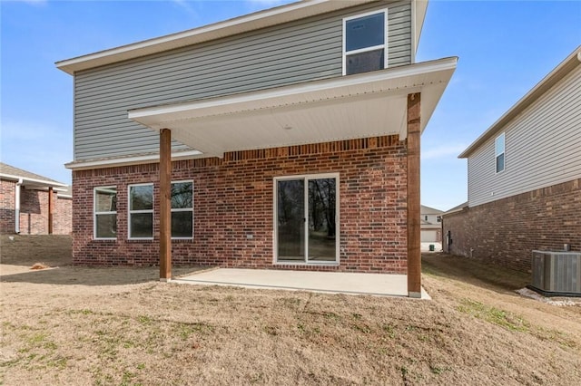 rear view of property with brick siding, central AC unit, a patio area, and a yard