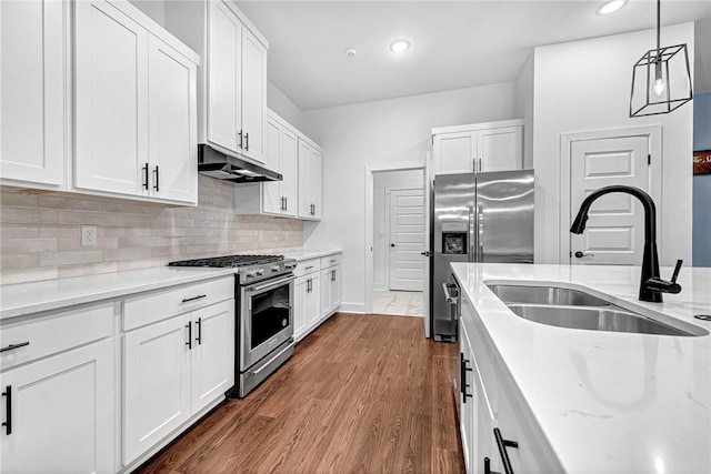 kitchen featuring appliances with stainless steel finishes, under cabinet range hood, a sink, white cabinets, and light stone counters