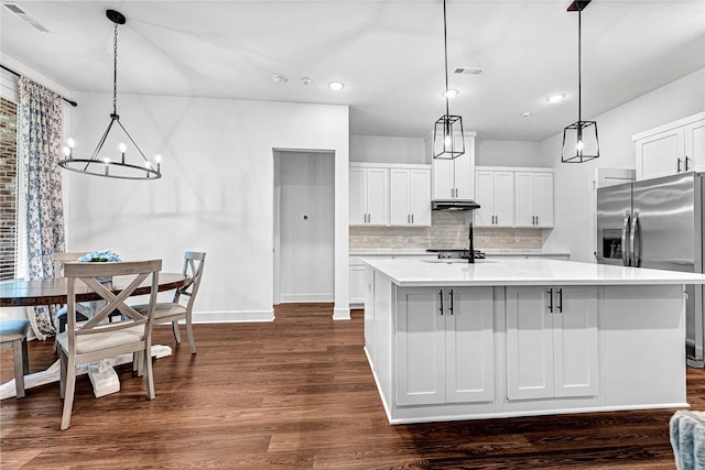 kitchen with appliances with stainless steel finishes, under cabinet range hood, a chandelier, dark wood-style floors, and light countertops