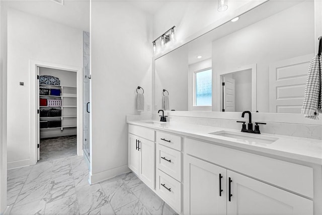 bathroom featuring marble look tile flooring, baseboards, double vanity, a spacious closet, and a stall shower