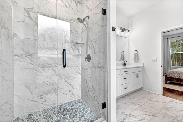 ensuite bathroom featuring a stall shower, marble finish floors, vanity, and baseboards