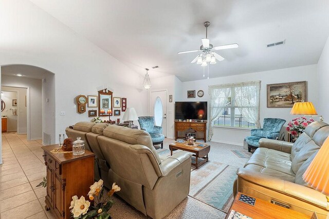 living area featuring arched walkways, ceiling fan, lofted ceiling, baseboards, and light tile patterned flooring