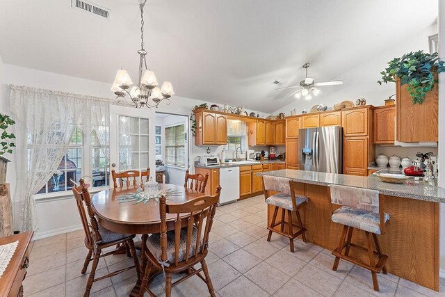 dining space featuring light tile patterned floors, lofted ceiling, a chandelier, and a ceiling fan