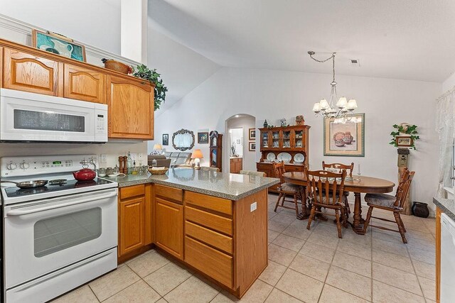 kitchen with white appliances, arched walkways, a peninsula, light tile patterned flooring, and a chandelier