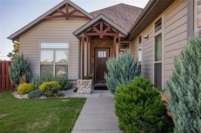 view of exterior entry with stone siding and a shingled roof