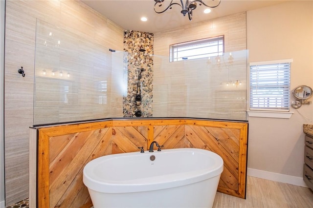 full bathroom with a freestanding bath, a chandelier, vanity, baseboards, and walk in shower