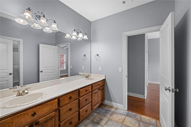 3907 NE Cadbury Ave, Bentonville, AR 72712 - bathroom with baseboards, double vanity, and stone finish flooring