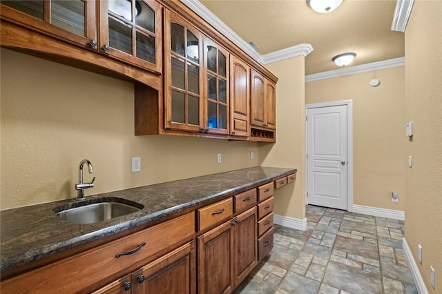 3907 NE Cadbury Ave, Bentonville, AR 72712 - kitchen featuring a sink, stone tile floors, ornamental molding, baseboards, and glass insert cabinets