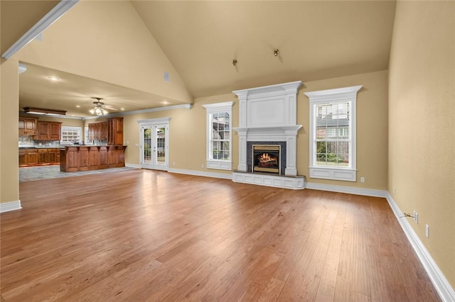 3907 NE Cadbury Ave, Bentonville, AR 72712 - unfurnished living room featuring ceiling fan, light wood-style flooring, healthy amount of natural light, a premium fireplace, and high vaulted ceiling