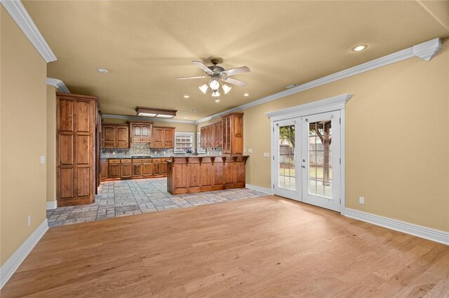 3907 NE Cadbury Ave, Bentonville, AR 72712 - kitchen featuring brown cabinetry, crown molding, french doors, baseboards, and a peninsula