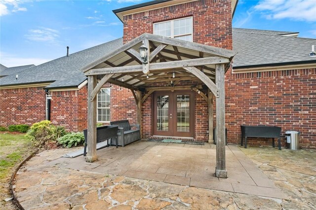 3907 NE Cadbury Ave, Bentonville, AR 72712 - back of house featuring french doors, a shingled roof, brick siding, and a patio