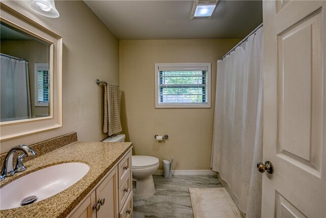 full bath featuring marble finish flooring, vanity, toilet, and baseboards