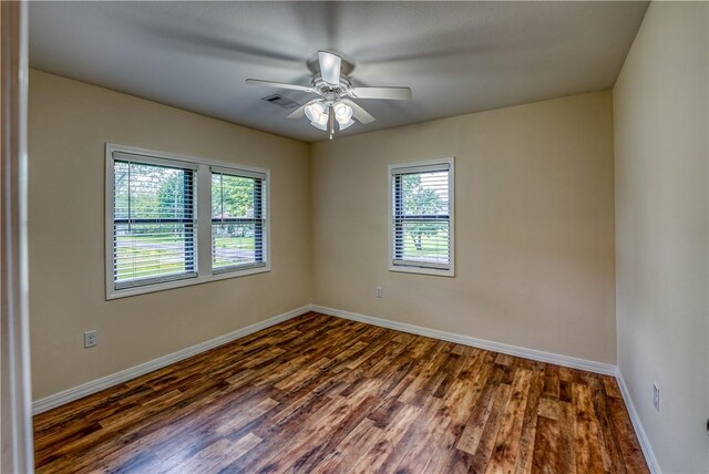 unfurnished room featuring plenty of natural light, dark wood finished floors, and baseboards