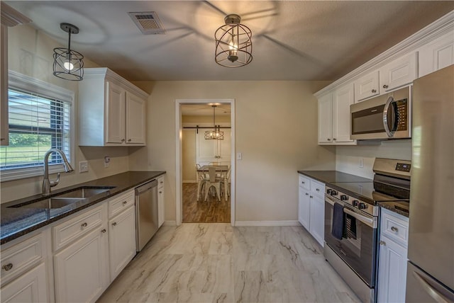 kitchen with appliances with stainless steel finishes, a sink, white cabinets, and dark stone countertops